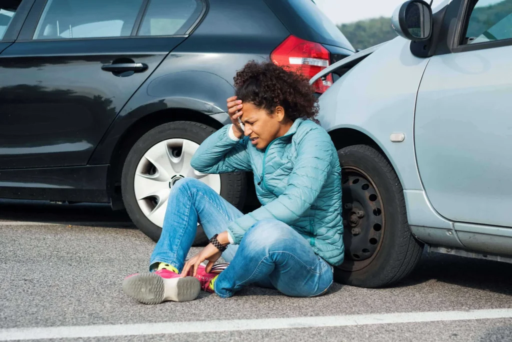 A person signing paperwork with a blue toy car sitting on a clipboard in the foreground.